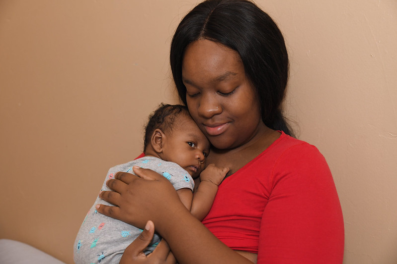 Mother holding a baby and looking content.