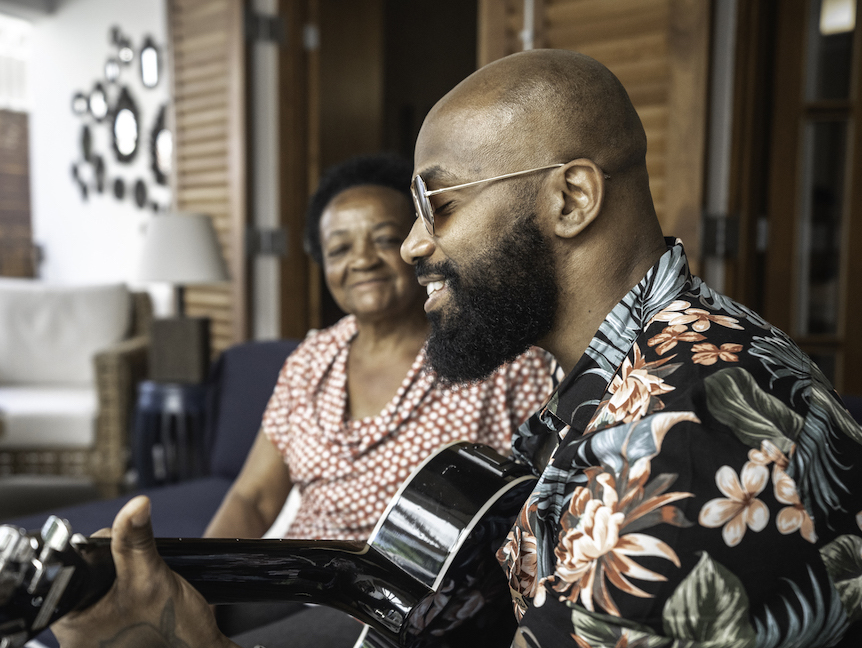 Image of a man playing a guitar and an older woman listening