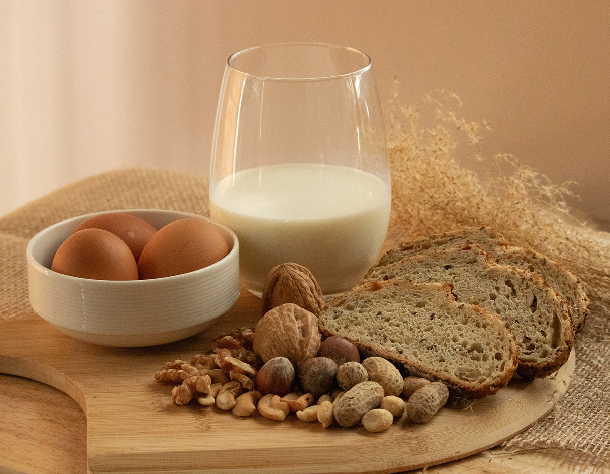 Peanuts, milk, eggs, wheat, cashews, walnuts, and hazelnuts on a wooden tray. Peanuts, milk, eggs, wheat, cashews, walnuts, and hazelnuts on a wooden tray.