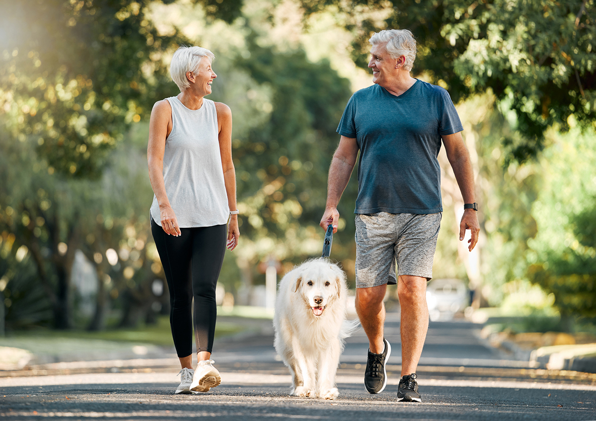 Image of an older woman and man walking a dog