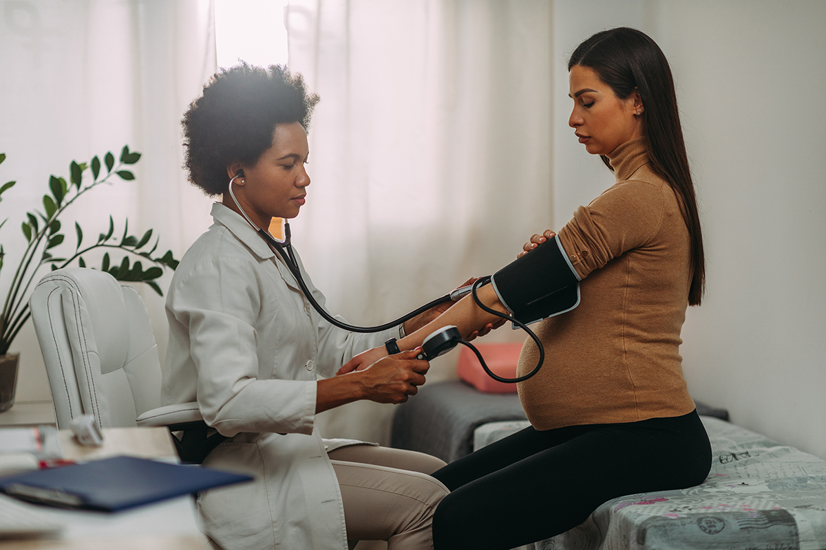Image of a doctor taking a pregnant patient’s blood pressure.