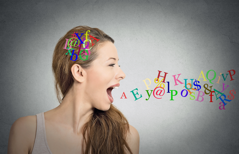 Side view portrait of a woman talking with alphabet letters in her head and coming out of her open mouth.