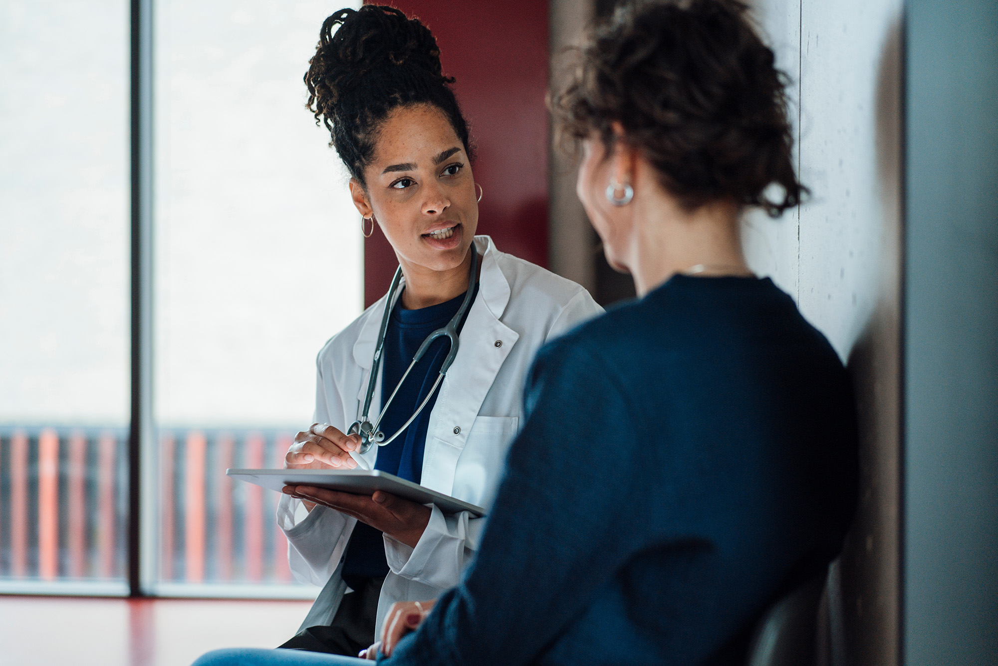 Doctor with a tablet speaking to a hospital patient. Doctor with a tablet speaking to a hospital patient.