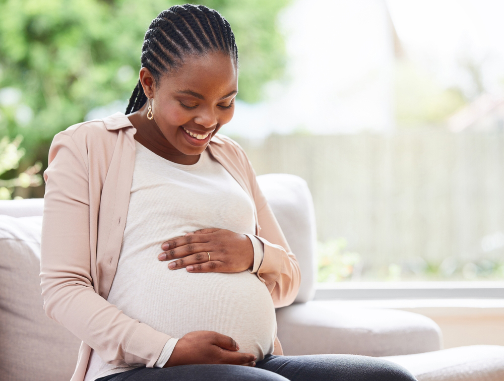Pregnant woman on sofa smiling down at her belly. Pregnant woman on sofa smiling down at her belly.