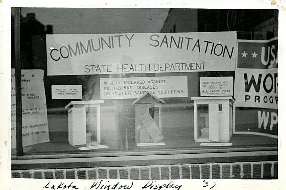 Health and Economy Exterior view of window display showing three model privies under a sign that reads "Community Sanitation."