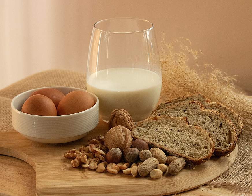  Peanuts, milk, eggs, wheat, cashews, walnuts, and hazelnuts on a wooden tray.