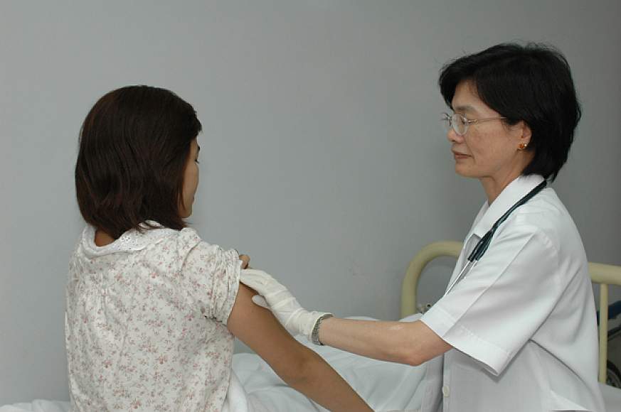 A female doctor giving an injection to a female patient A female doctor giving an injection to a female patient.