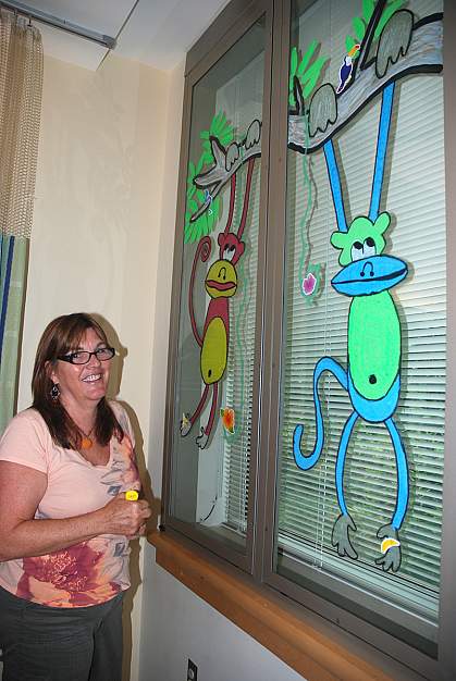 Annette Weller shows a monkey tree she painted on a Clinical Center window Annette Weller, a self-taught artist, shows a monkey tree she painted on a Clinical Center window.