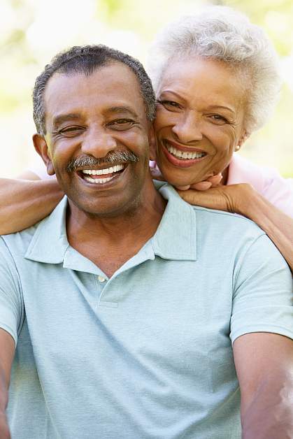 Portrait of romantic senior African American couple in park A retired couple smiling for the camera.