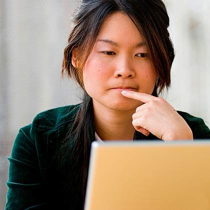 A young woman thinking as she looks at a laptop computer screen A young woman thinking as she looks at a laptop computer screen.