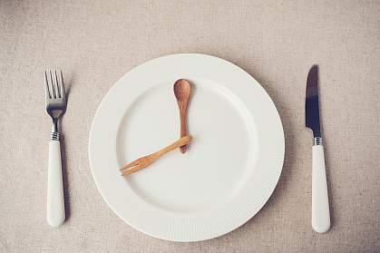 White plate with knife and fork representing hands of a clock. White plate with knife and fork representing hands of a clock.