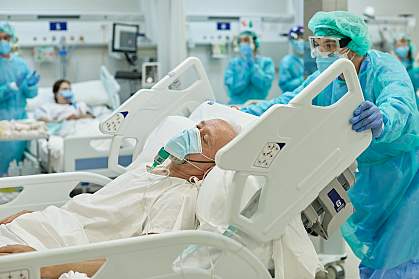 Healthcare worker wheeling hospital bed with senior COVID-19 patient on ventilator Healthcare worker wheeling hospital bed with senior COVID-19 patient on ventilator