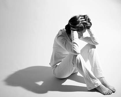 Photo of a woman sitting with her hands on her head Photo of a woman sitting with her hands on her head