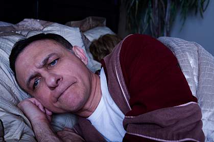 Photo of an angry man lying awake in bed Photo of an angry man lying awake in bed