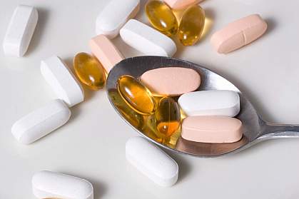 Photo of multiple vitamin pills and spoon Photo of multiple vitamin pills and spoon