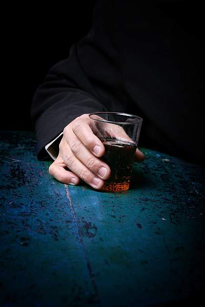 Photo of a hand holding a glass with an alcoholic drink Photo of a hand holding a glass with an alcoholic drink