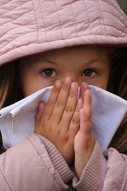 Photo of a child in a winter coat blowing her nose Photo of a child in a winter coat blowing her nose