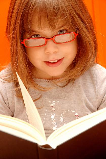Photo of a young girl reading with glasses Photo of a young girl reading with glasses