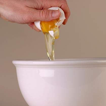 Photo of hand breaking egg into bowl Photo of hand breaking egg into bowl