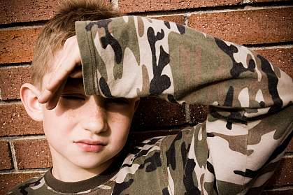 photo of a young boy shielding his eyes from a bright light photo of a young boy shielding his eyes from a bright light