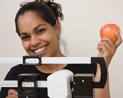 Photo of a young woman standing on a scale, holding an apple Photo of a young woman standing on a scale, holding an apple
