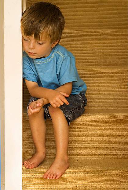 a photo of a young boy, looking down, seated on some stairs a photo of a young boy, looking down, seated on some stairs