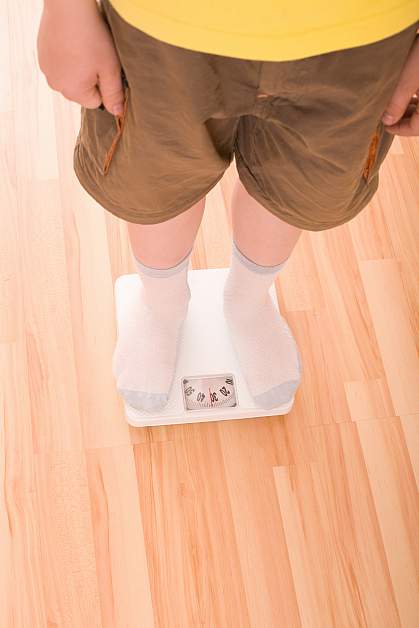 Photo of a boy standing on a bathroom scale Photo of a boy standing on a bathroom scale
