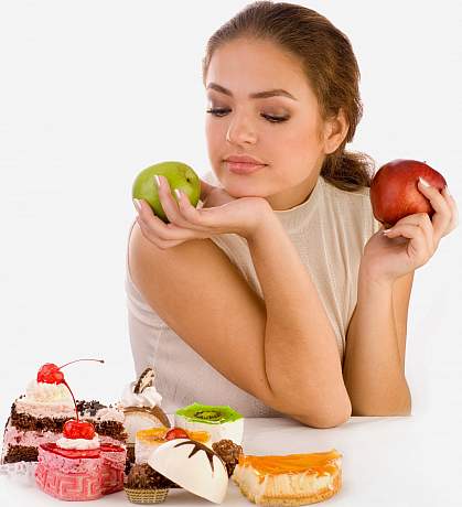 photo of a woman holding two apples but looking down at some sweets photo of a woman holding two apples but looking down at some sweets