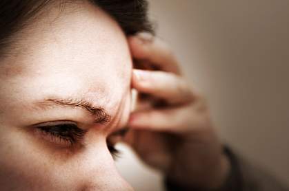 Photo of a woman holding her hand to her head Photo of a woman holding her hand to her head