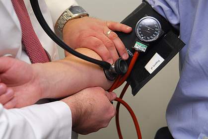 Photo of a doctor holding an arm in a blood pressure cuff Photo of a doctor holding an arm in a blood pressure cuff