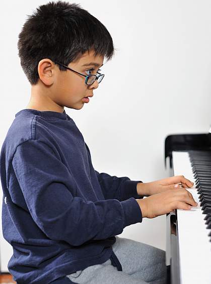 Photo of a boy playing a piano Photo of a boy playing a piano