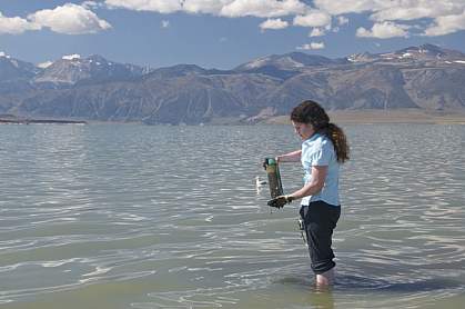 Photo of a woman standing in shallow water with a specimen jar Photo of a woman standing in shallow water with a specimen jar