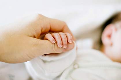 Photo of a newborn's fingertips held by an adult’s hand Photo of a newborn's fingertips held by an adult’s hand