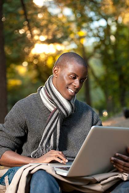 Photo of a young African-American man looking at a computer and smiling Photo of a young African-American man looking at a computer and smiling