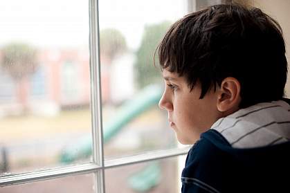 Photo of a young boy looking out a window Photo of a young boy looking out a window