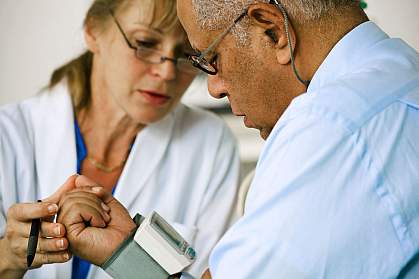 Photo of doctor taking man's blood pressure.