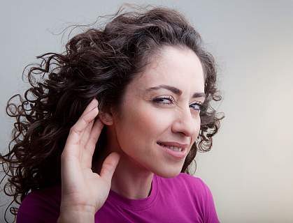 Photo of a young woman cupping her hand to her ear Photo of a young woman cupping her hand to her ear