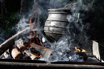 Photo of an iron pot on a smoking fire