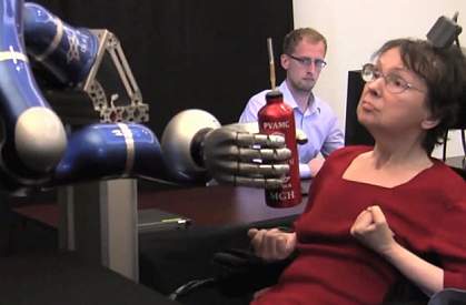 A woman controlling a robotic arm to grasp a bottle. A woman controlling a robotic arm to grasp a bottle.
