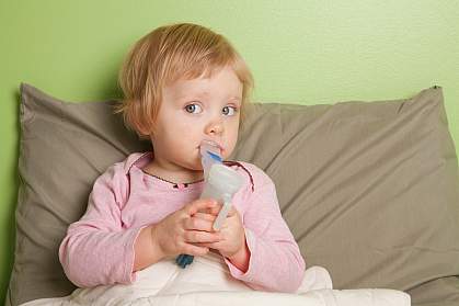 Young girl inhaling mist through a mouthpiece.