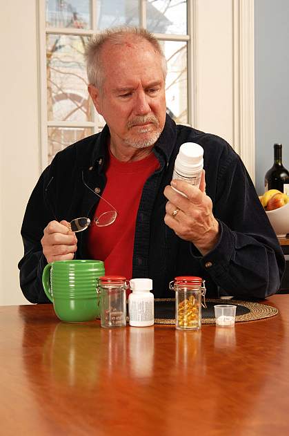 Man reading the label on a vitamin bottle.