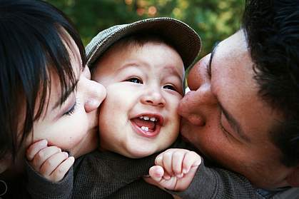 Parents kissing child.