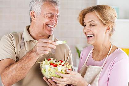 Happy senior couple eating salad in the kitchen. Happy senior couple eating salad in the kitchen.