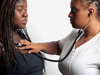 Doctor using a stethoscope to examine an overweight African-American woman Doctor using a stethoscope to examine an overweight African-American woman.