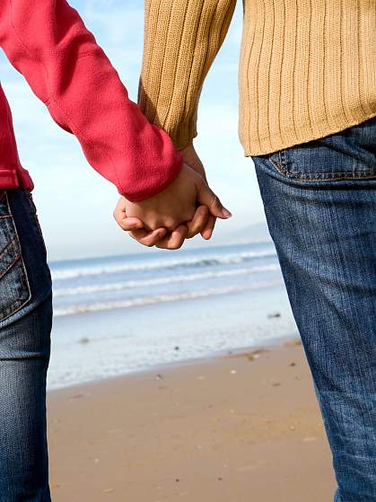 Couple holding hands on beach in winter Couple holding hands on beach in winter
