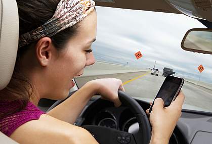 Young woman driving on highway while using smart phone Young woman driving on highway while using smart phone.