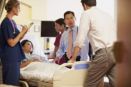 Medical team meeting around female patient in hospital room Medical team meeting around female patient in hospital room.