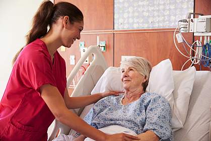 Nurse talking to an older woman in a hospital bed Nurse talking to an older woman in a hospital bed