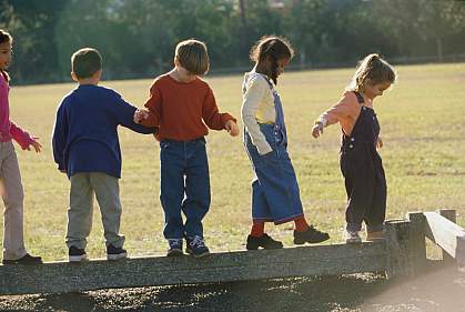 Group of children walking on a wooden log