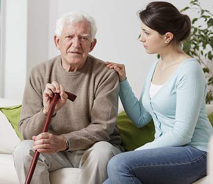 Elderly man with walking stick and caregiver